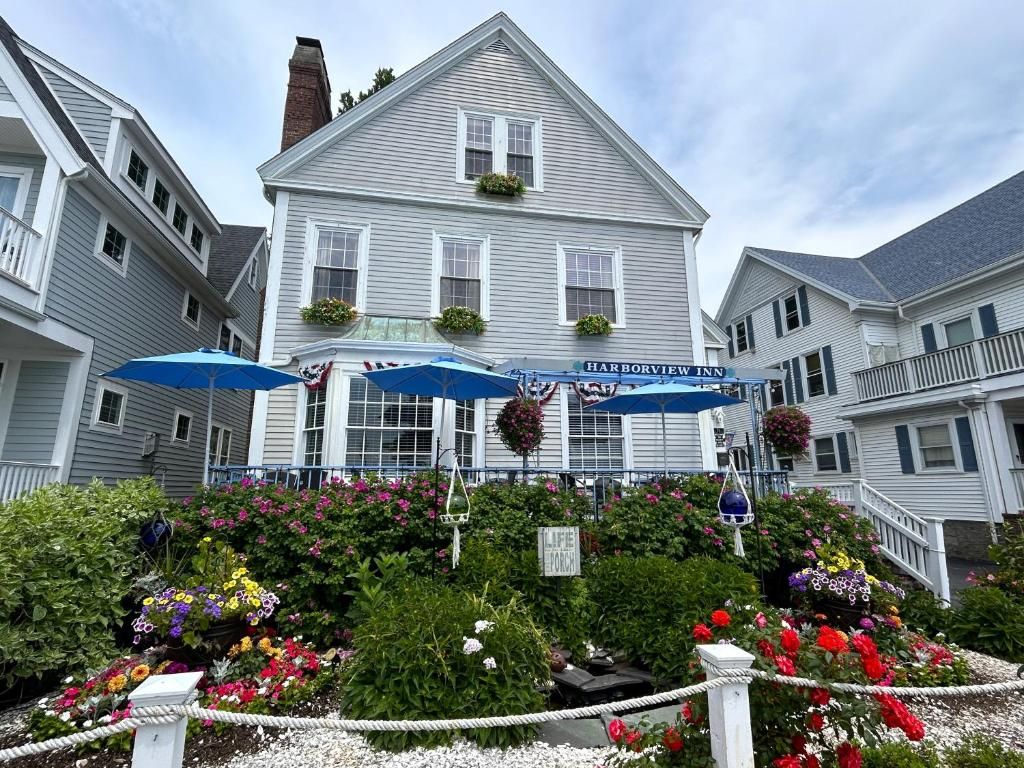 Ein zweistöckiges Gebäude mit der Aufschrift 'Harborview Inn'. Vor dem Gebäude befinden sich zwei Sonnenschirme und eine Blumenschmuck verzierte Leine.