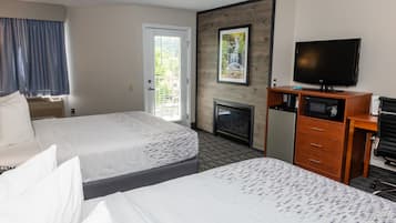 Une chambre d’hôtel avec deux lits, une télévision, une cheminée et une porte donnant sur un balcon.
