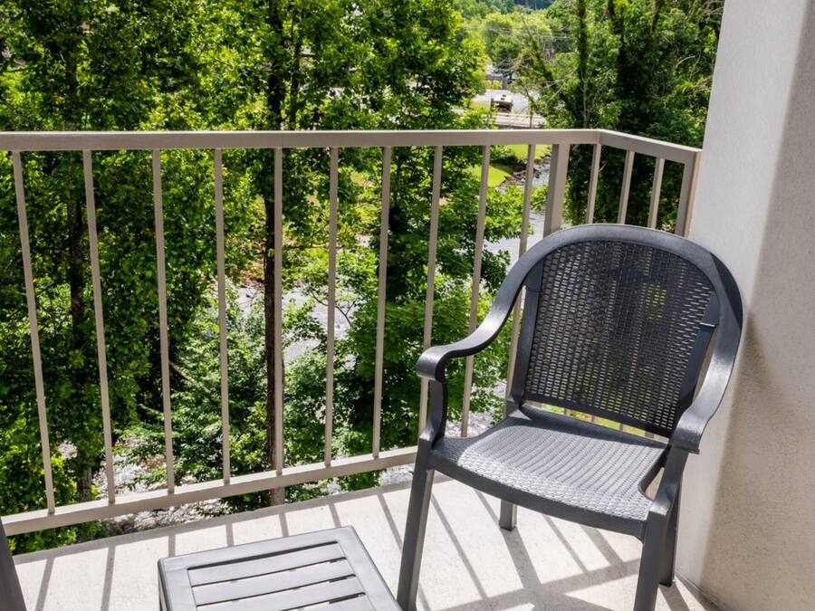 Un balcón con una silla y una mesa pequeña, con vistas a un paisaje verde y exuberante.