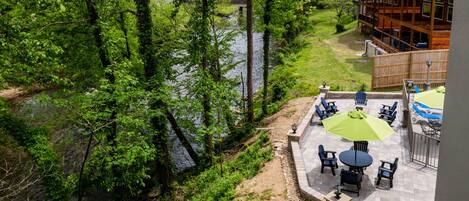 Une vue sur le lac, avec un espace patio comprenant des sièges d’extérieur et un chalet en bois en arrière-plan.