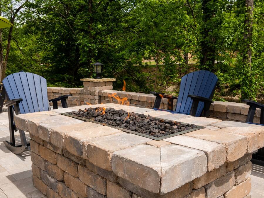 An outdoor seating area with a stone fire pit and Adirondack chairs.