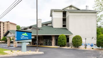 A Twin Mountain hotel with a modern design, featuring a prominent entrance, a landscaped area with trimmed bushes, and a visible swimming pool area.