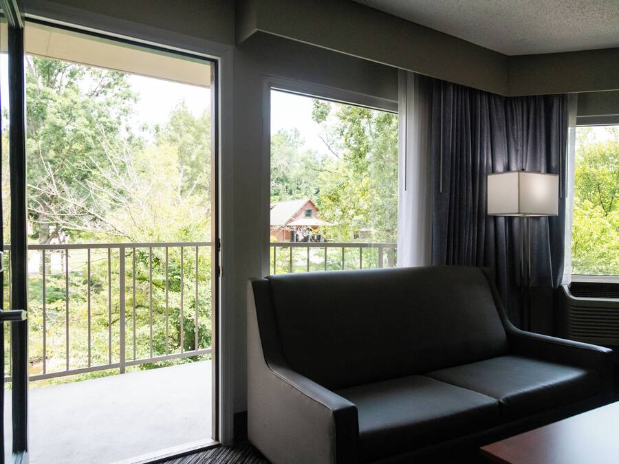 A hotel room with a sofa, a table, and a window with curtains.