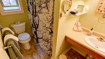 A bathroom with a toilet, shower curtain, sink, and towel rack.