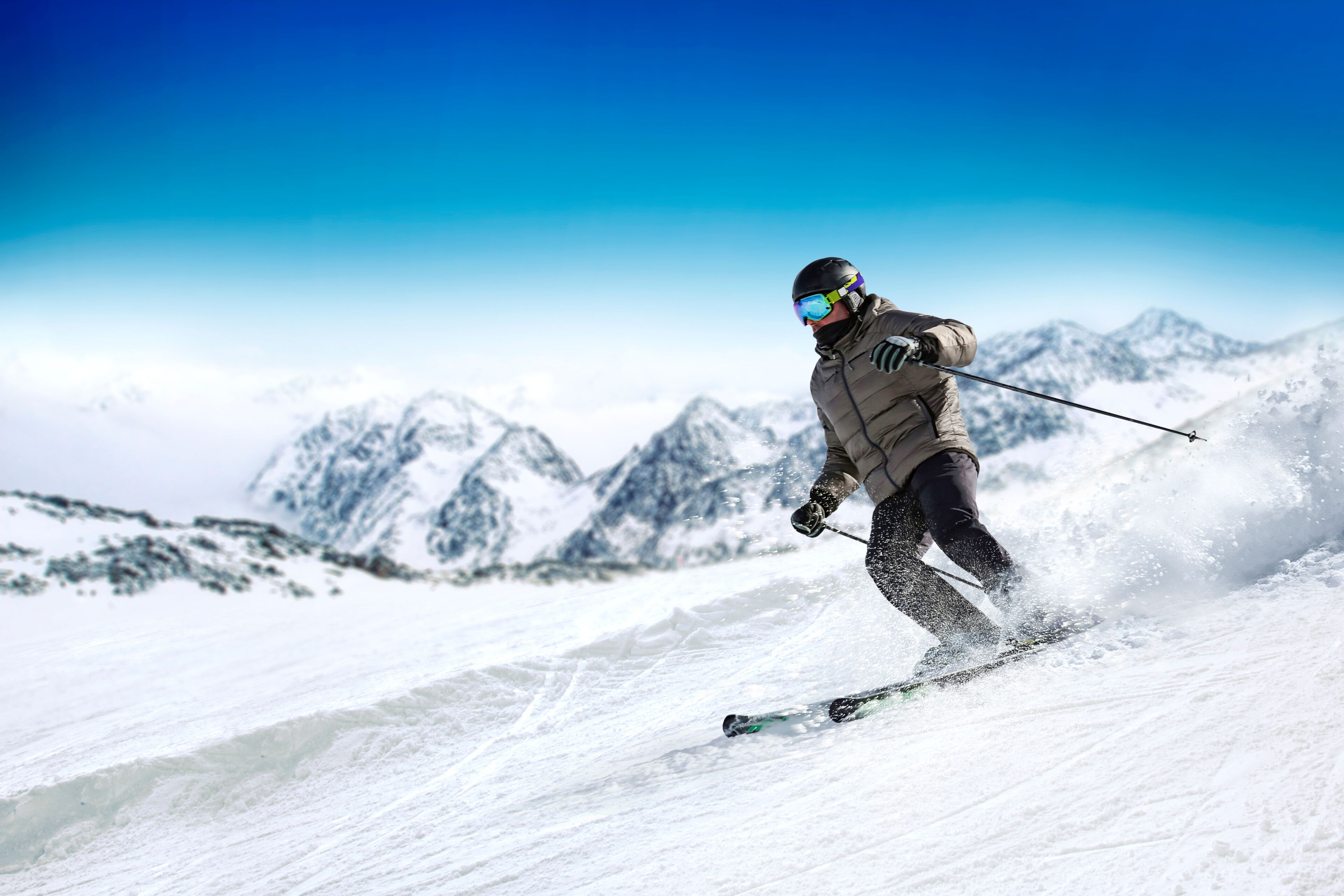 A person skiing down a snowy slope with mountains in the background.