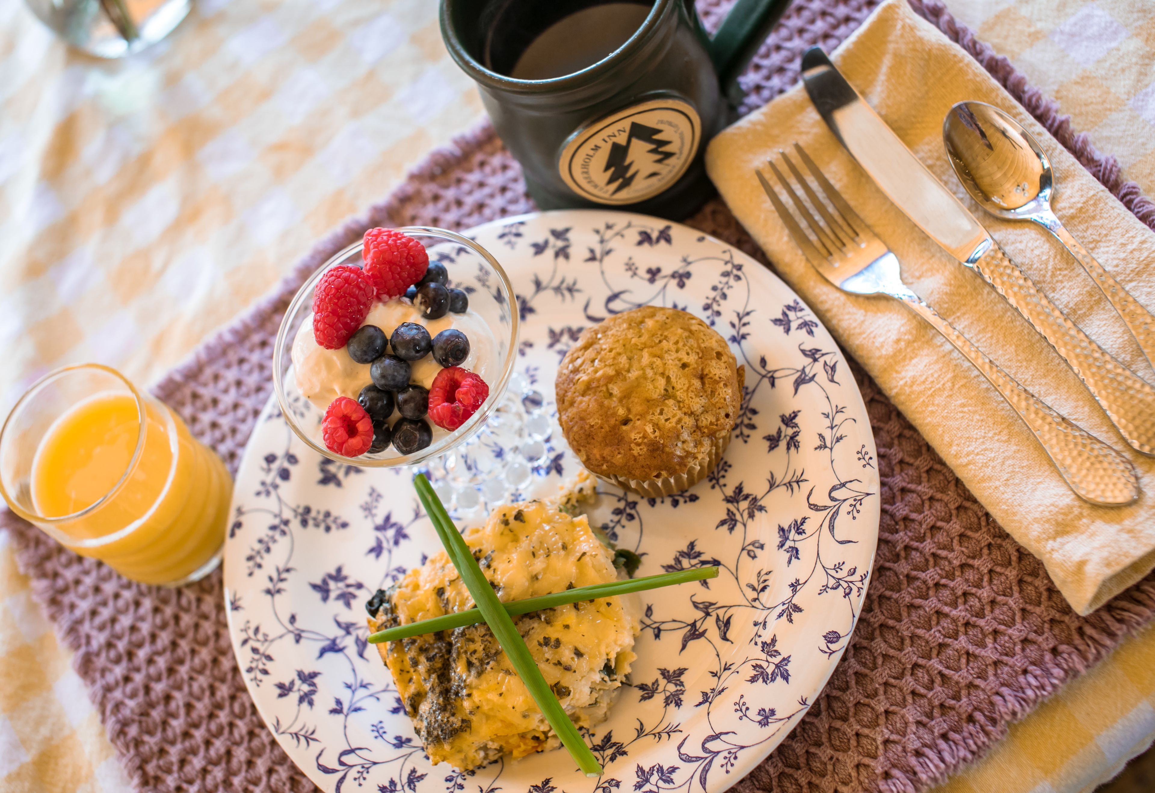 A breakfast plate with pancakes, a muffin, and a glass of orange juice.