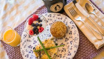 A breakfast plate with pancakes, a muffin, and a glass of orange juice.