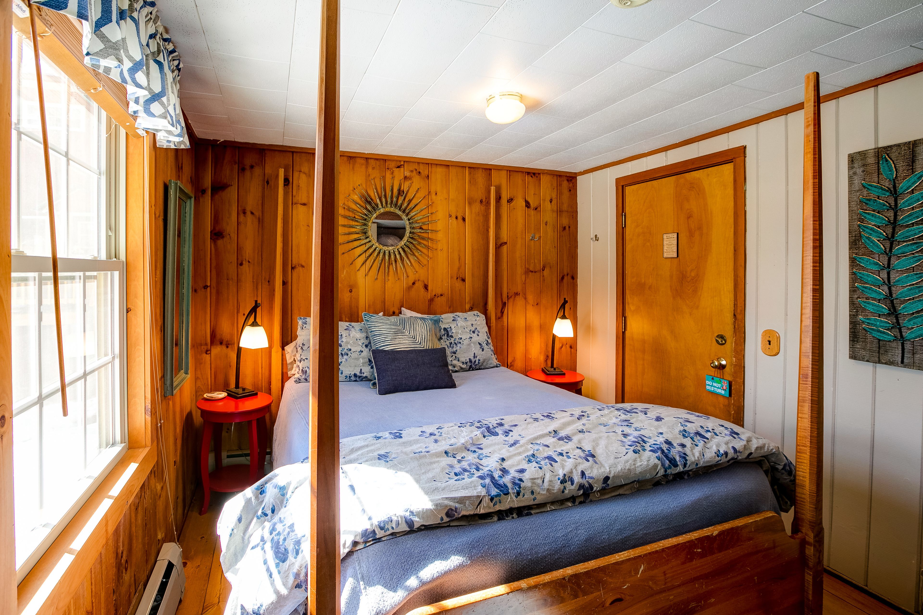 Une chambre à coucher aux murs lambrissés, avec un lit, deux lampes de chevet, une table de chevet et une porte dotée d’un trou de serrure.