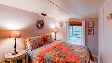 Une chambre à coucher avec un lit, deux lampes de chevet, une fenêtre avec des rideaux et des éléments décoratifs sur les murs.