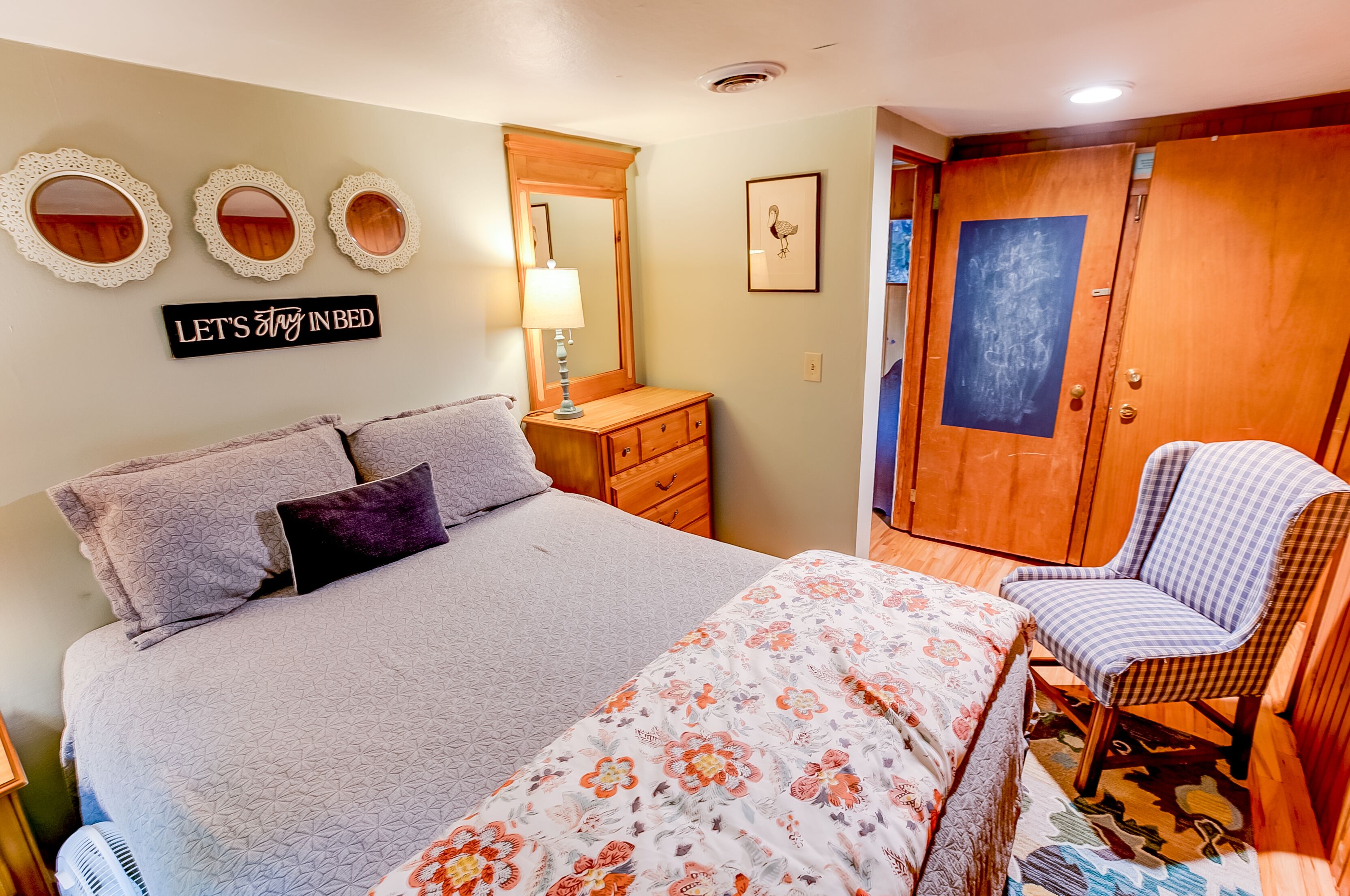 A neatly arranged bedroom with a bed, a chair, a dresser, and a wardrobe.