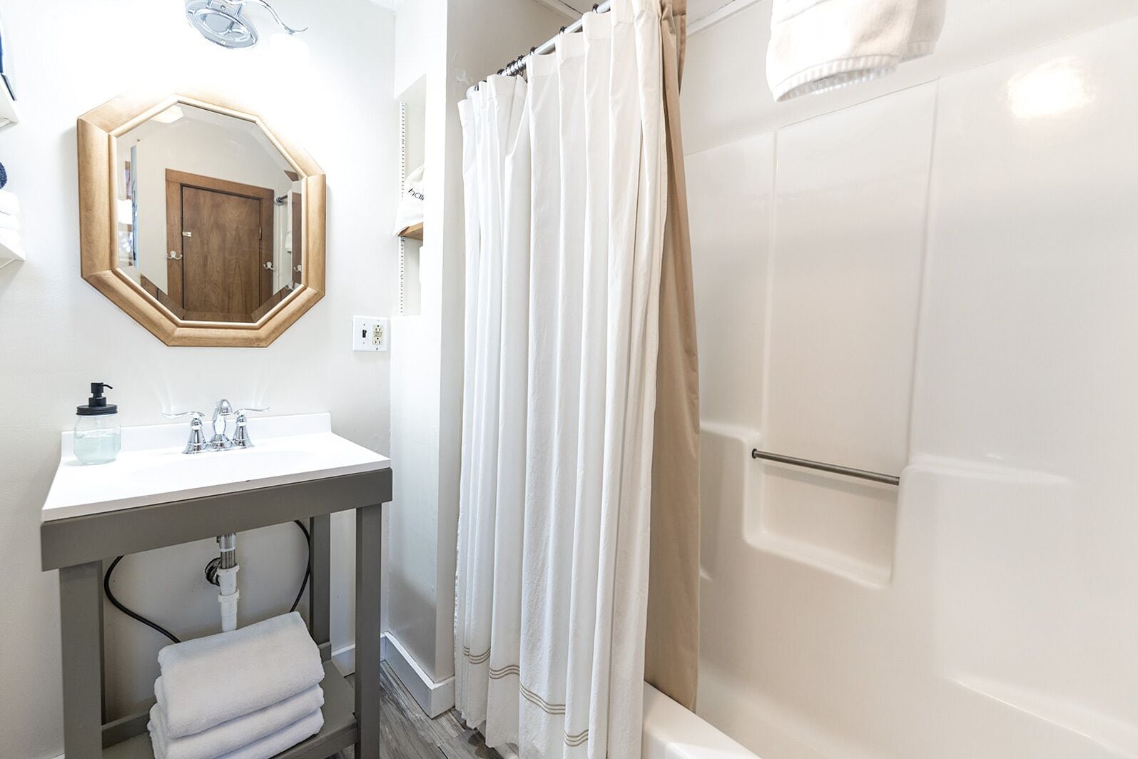 Une salle de bain avec un lavabo blanc, un miroir et un rideau de douche.