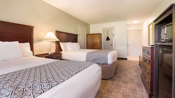 A hotel room with two beds, a dresser, a television, and a lamp.