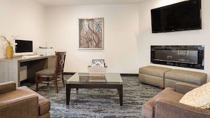 A hotel room with a desk, a computer, a television, a sofa, and a coffee table. - SureStay Hotel by Best Western Thomson (Thomson)