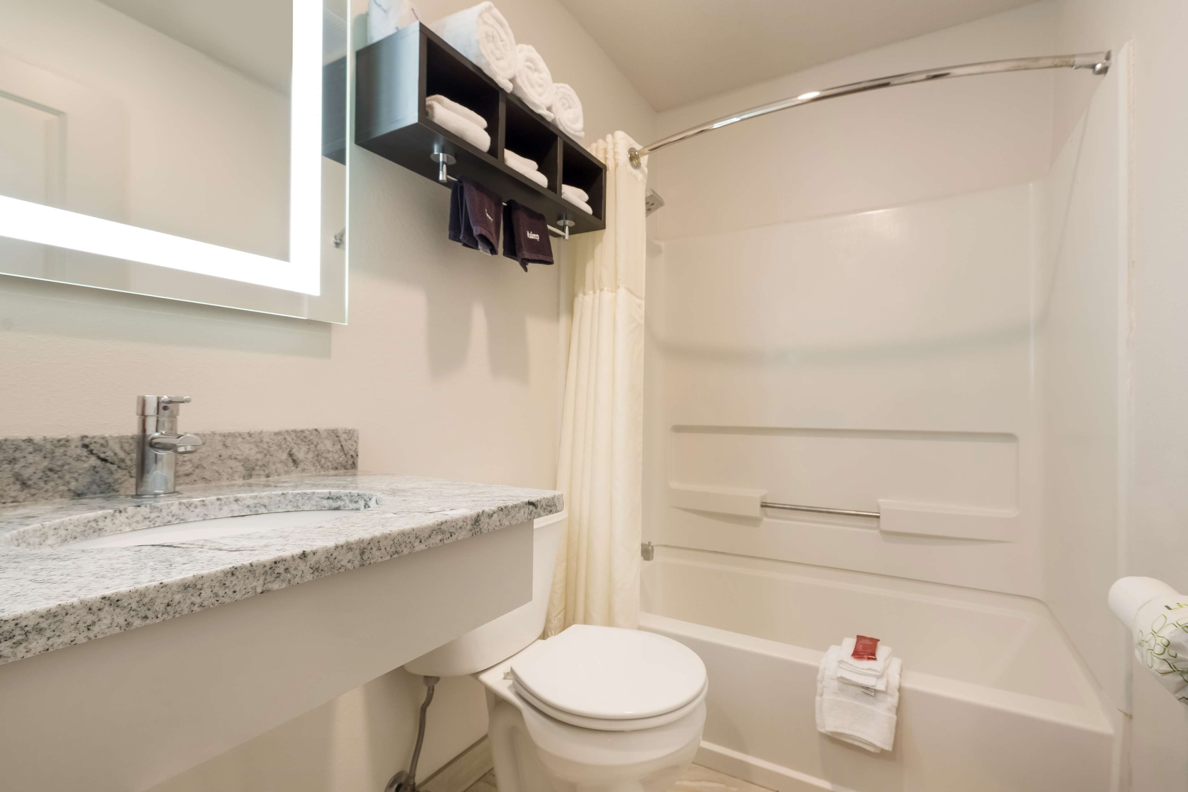 A bathroom with a marble sink, a toilet, a shower with a glass door, and a towel rack with folded towels.