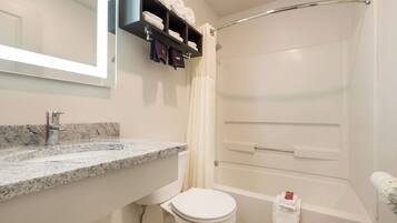 A bathroom with a marble sink, a toilet, a shower with a glass door, and a towel rack with folded towels.