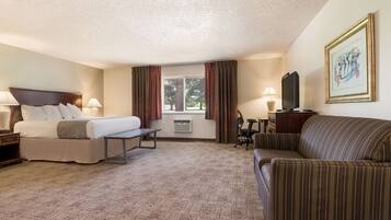 A hotel room with a bed, a sofa, a desk, and a window with curtains.