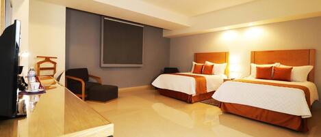 Habitación de hotel con dos camas, un escritorio con silla, televisor y ventana grande.