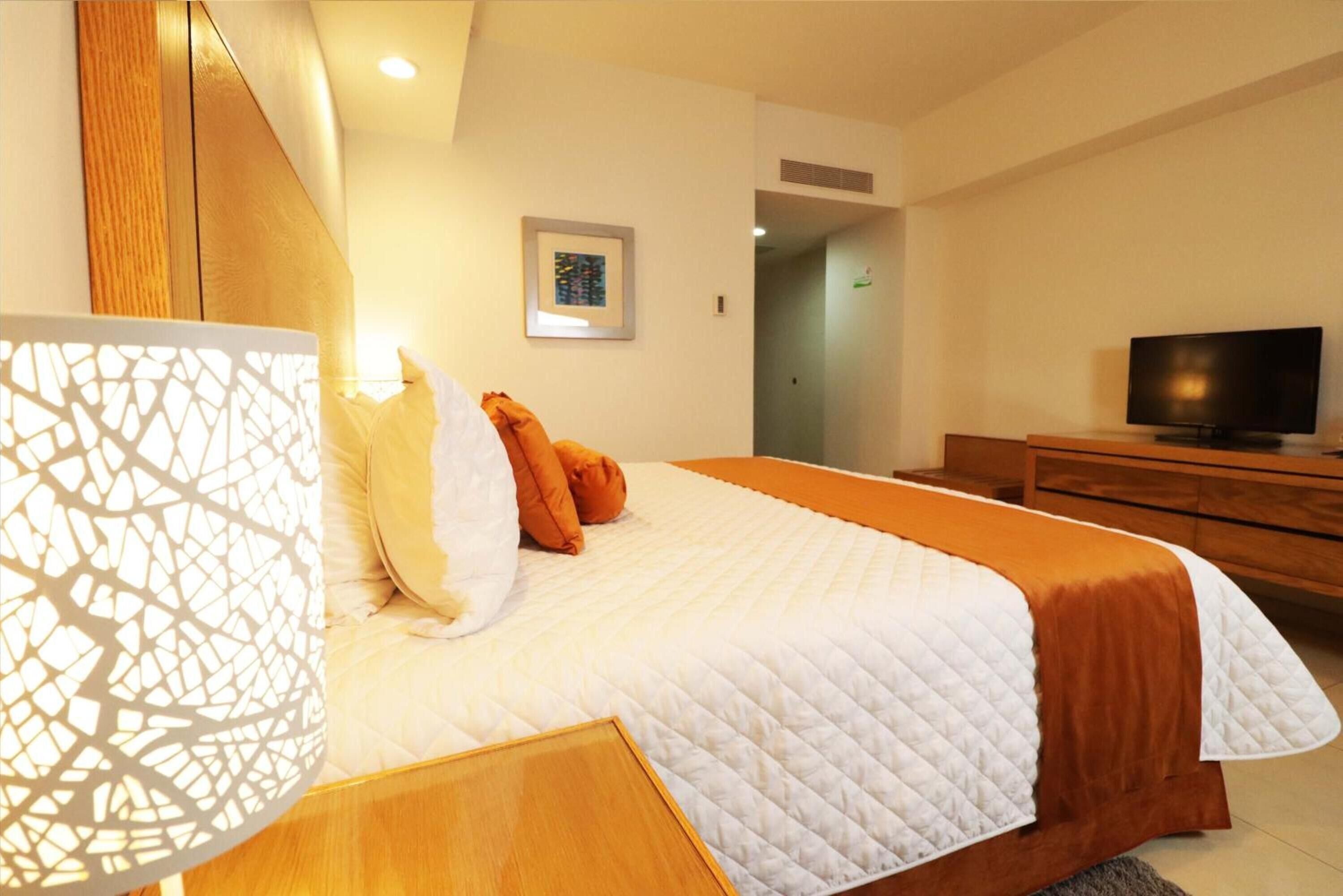 Une chambre d’hôtel avec un grand lit, une télévision et une commode en bois.