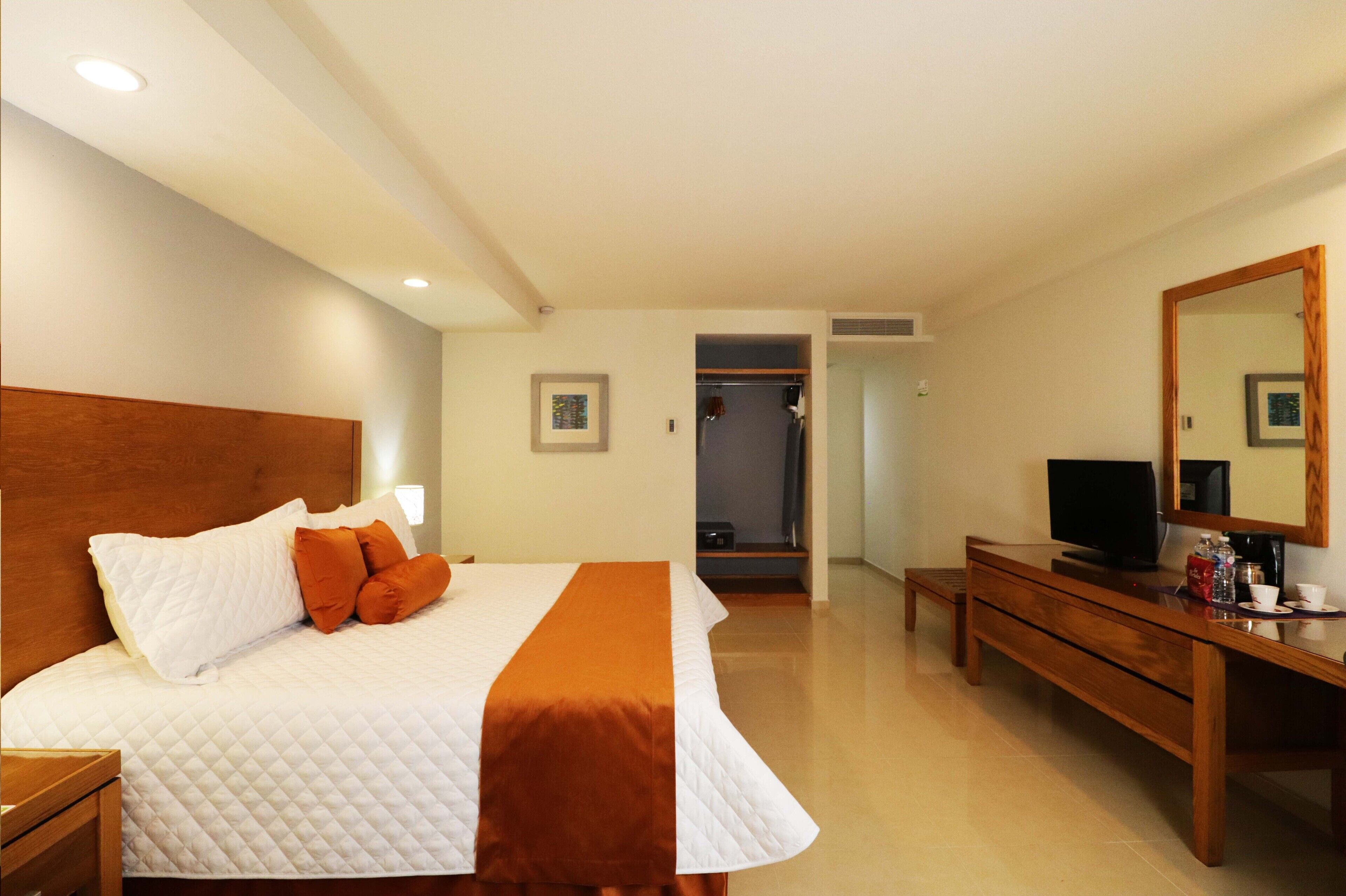 Una habitación de hotel con una cama, un aparador de madera, un televisor y un espejo.