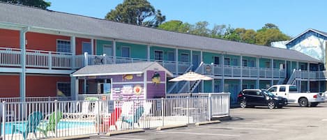 A motel with a pool area, multiple balconies, and a parking lot with cars.