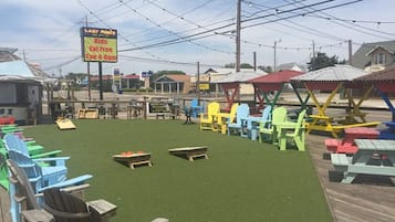 Un patio con sillas Adirondack de colores, un cartel anunciando comida gratis y un césped.