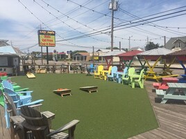 A patio area with colorful Adirondack chairs, a sign advertising free food, and a grassy lawn.