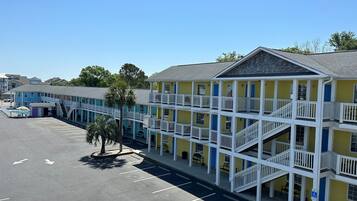 Un motel de varios pisos con balcones y un estacionamiento.