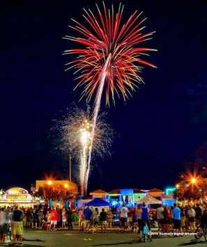 A nighttime scene with a large crowd gathered to watch fireworks. - Pirates Cove (Carolina Beach)