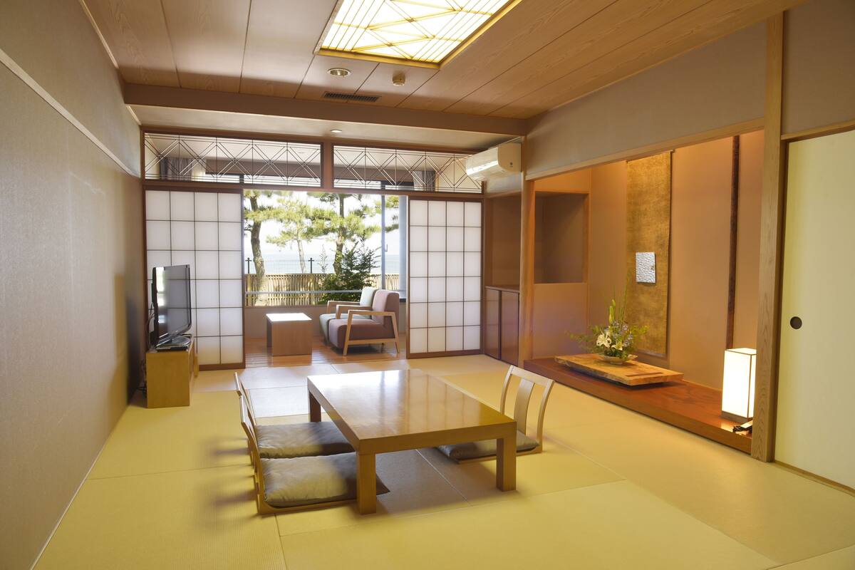 A traditional Japanese room with tatami flooring, a low table, and a television.