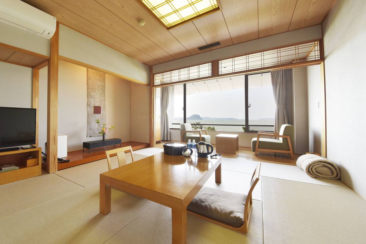 A traditional Japanese-style living room with tatami flooring, a low wooden table, and a television.
