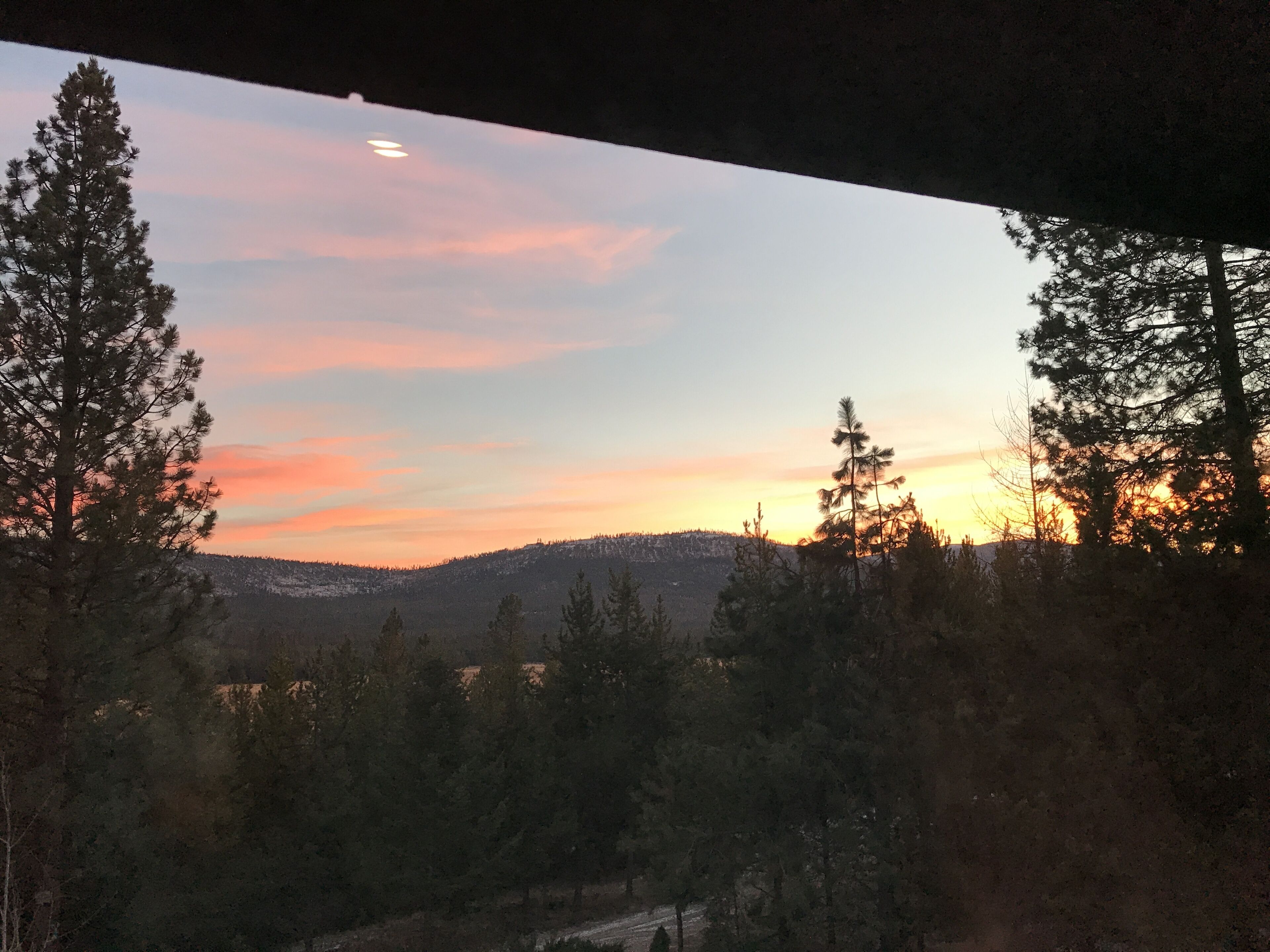 A view of a forested landscape with a sunset in the background.