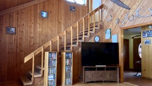 Un interior de madera con una escalera, un televisor de pantalla plana y una decoración con cabeza de venado.