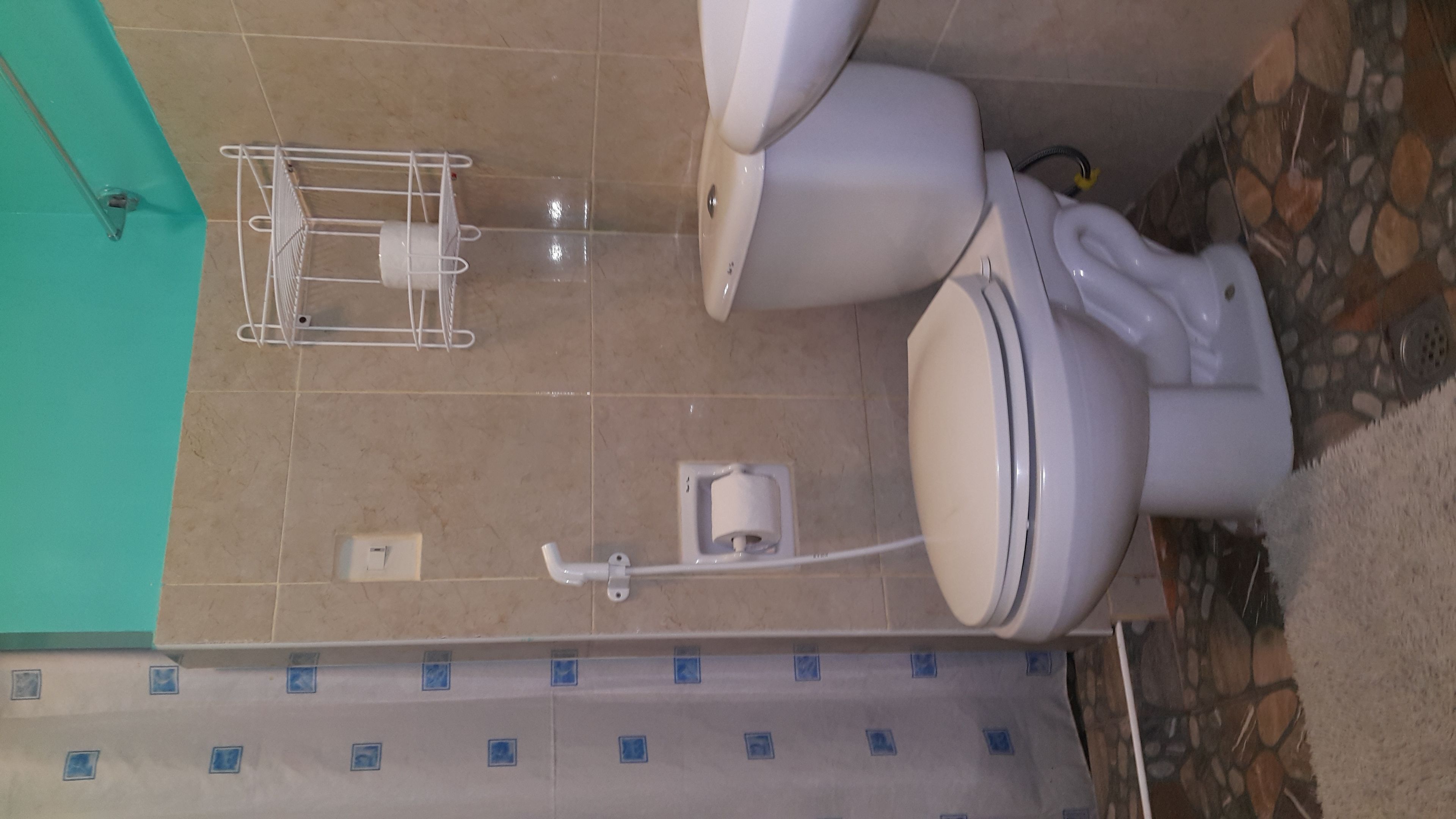 Un baño con inodoro, secador de manos y dispensador de toallas de papel.