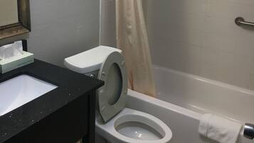 A bathroom with a toilet, sink, and shower area.