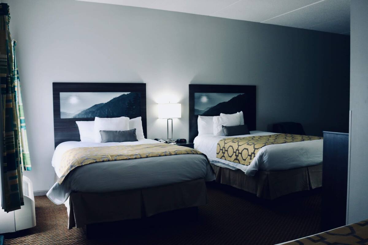 Une chambre d’hôtel avec deux lits, une table de chevet, une lampe et une vue sur les montagnes.