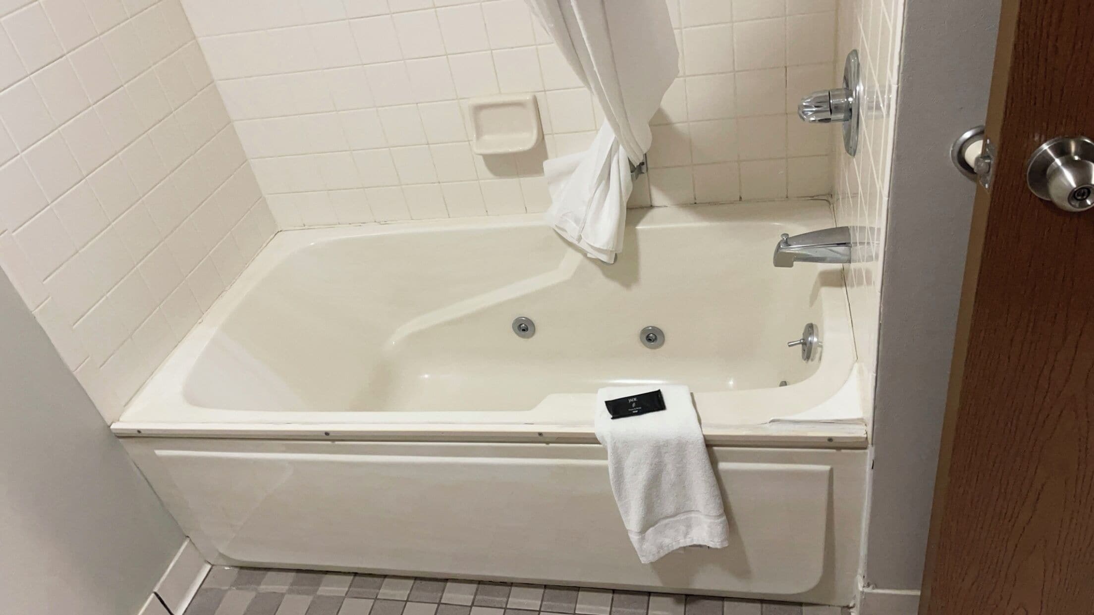 A bathroom with a bathtub, a towel rack, and a shower curtain.