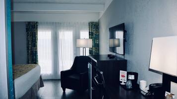 Et hotelværelse med en seng, et skrivebord, en stol, en kaffemaskine og et skilt, der angiver room service levering.