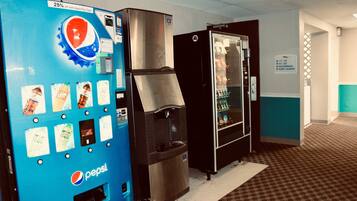 A vending machine and a refrigerator in a hotel lobby.