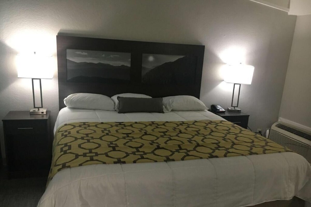 A hotel room with a bed, two bedside lamps, a telephone, and a wall-mounted heater.