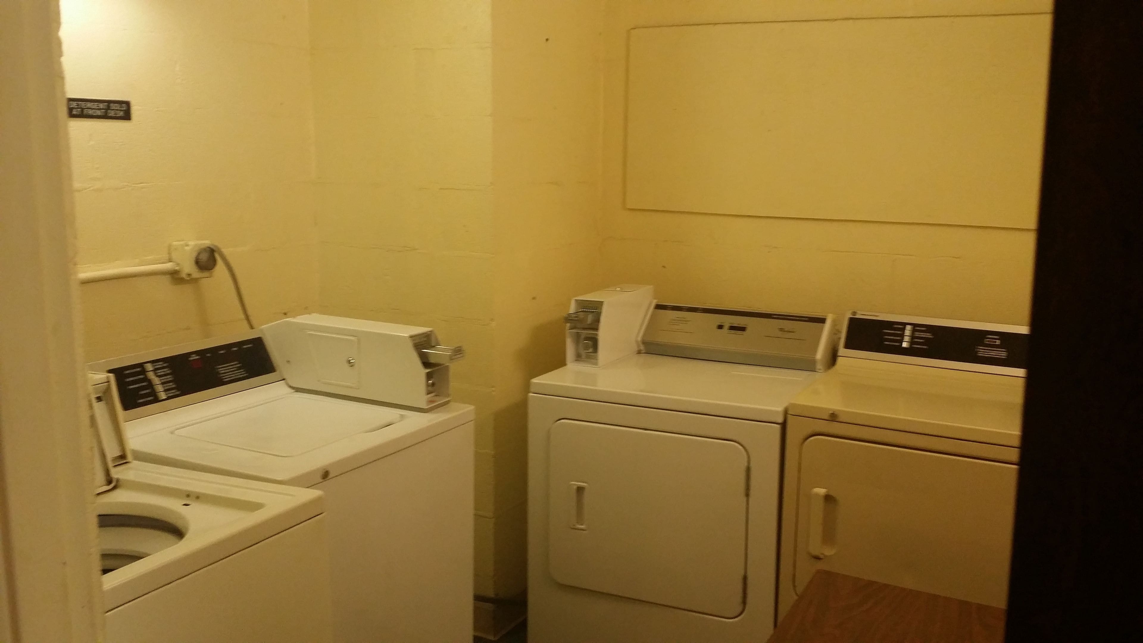 Une buanderie équipée d’un lave-linge à chargement frontal, d’un lave-linge à chargement par le dessus et d’un sèche-linge.