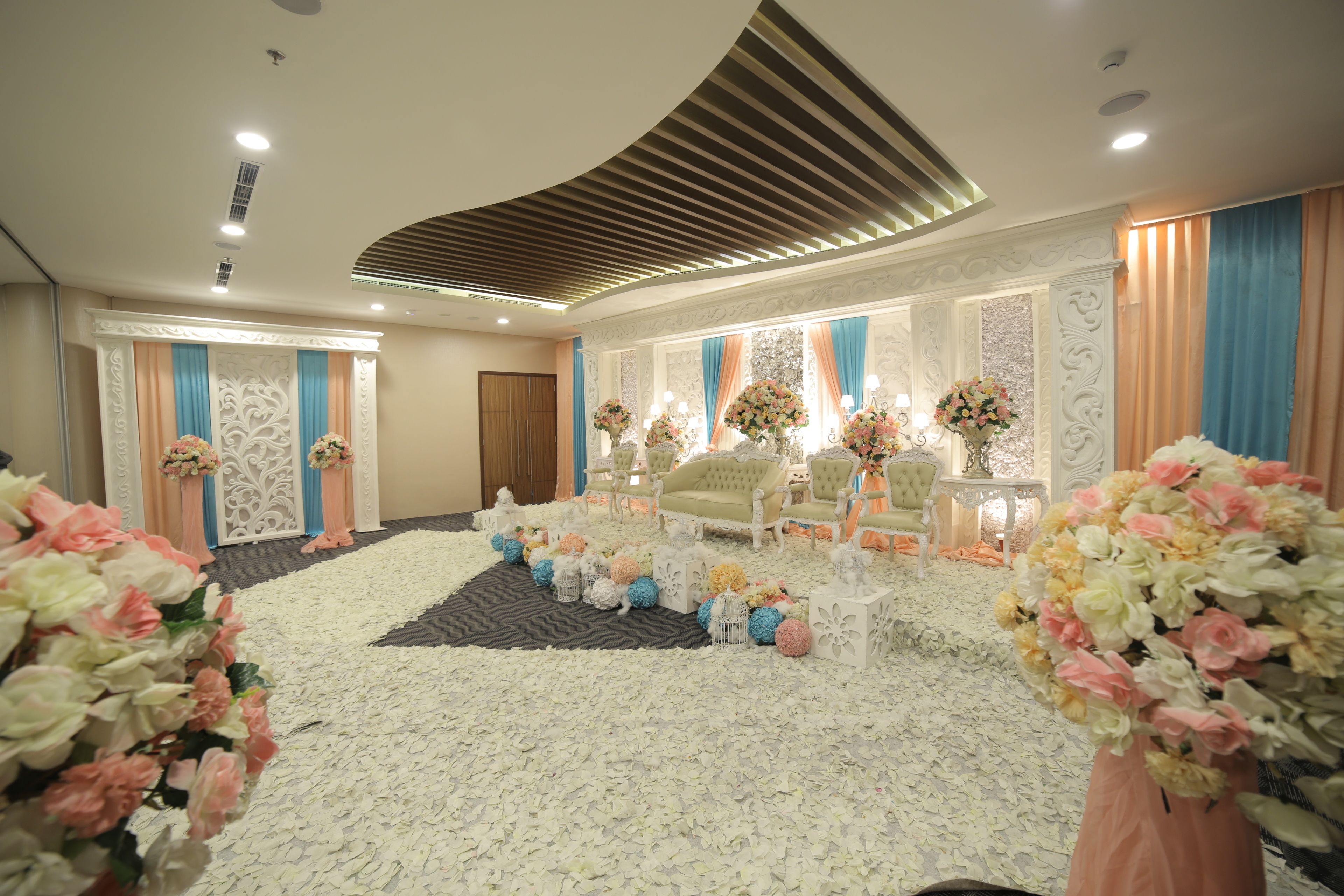 A formal event space with a stage, seating, and floral decorations.