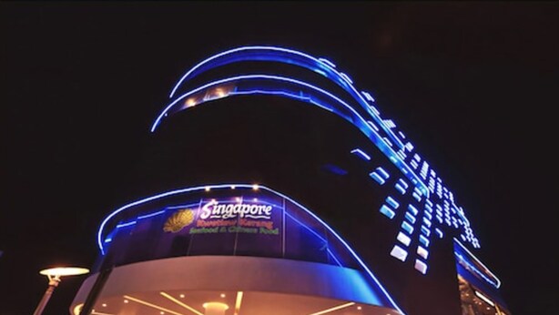 Un edificio moderno con fachada curva y señalización iluminada que dice "Singapore".