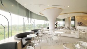 Un interior moderno con un sofá curvo, mesas redondas y una zona de bar central.