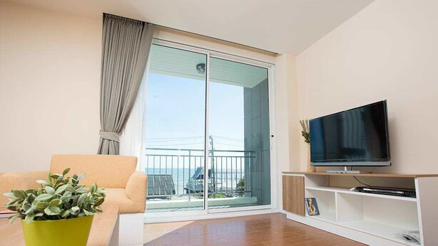 Sala moderna com sofá, televisão, planta e varanda com vista.