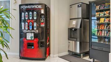 Máquina expendedora con dispensador de bebidas y refrigerador lleno de aperitivos.
