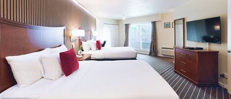 A hotel room with two beds, a TV, a dresser, and a window with curtains.