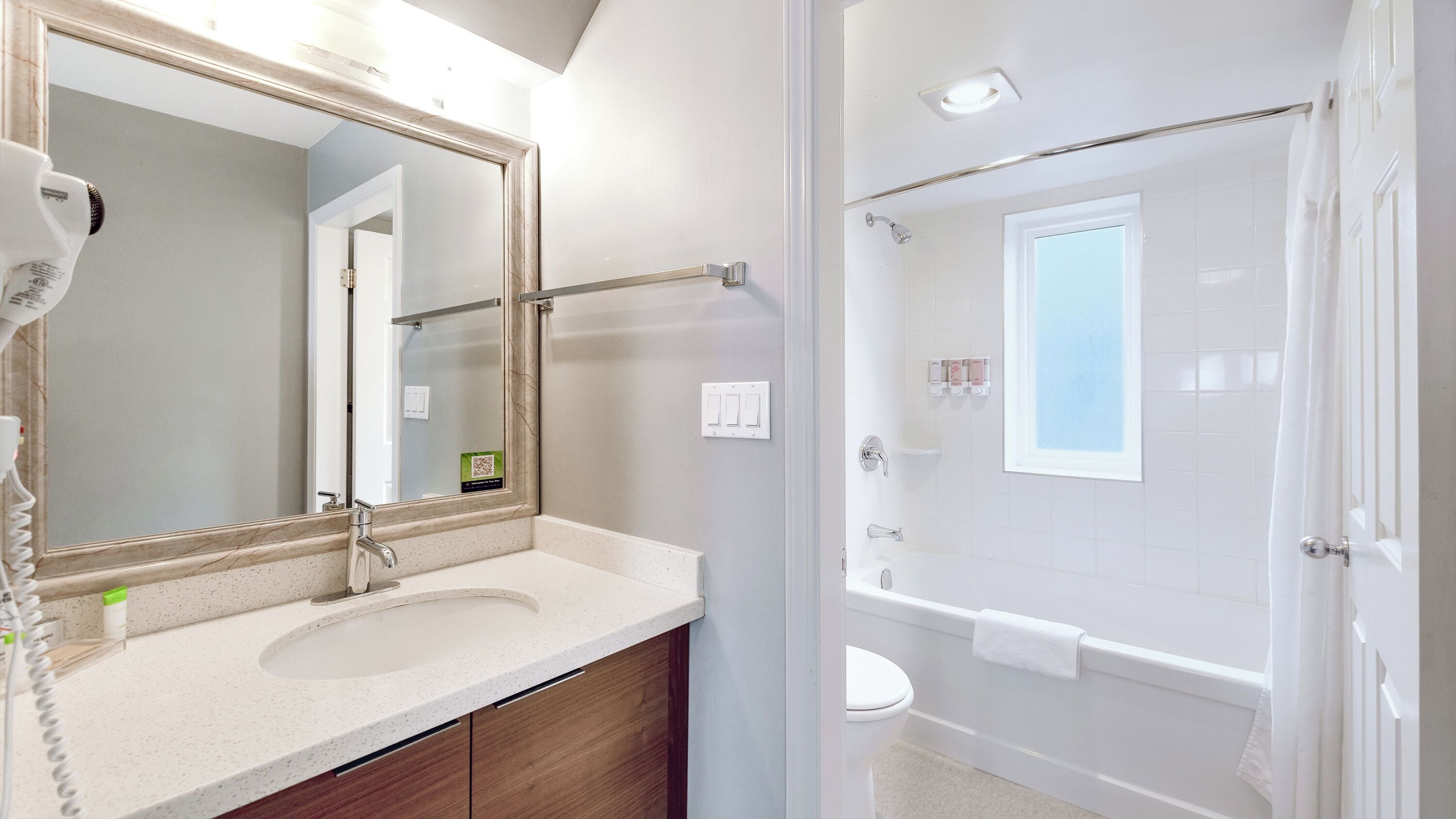 Un baño con un espejo grande, un secador de pelo, un lavabo y una zona de ducha.