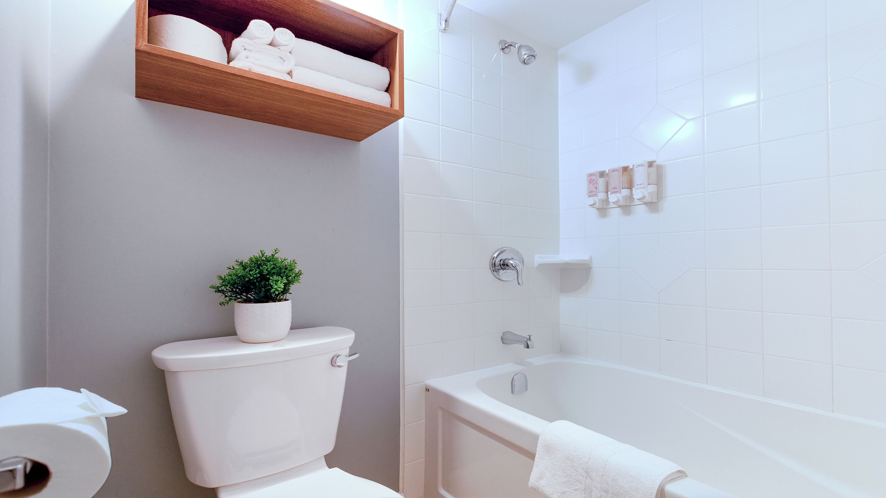 Et badeværelse med toilet, badekar og en hylde med håndklæder.