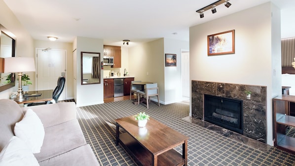 A modern living room with a fireplace, a dining area, and a kitchen.