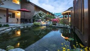 A serene courtyard with a koi pond, outdoor seating, and a well-lit patio area. - Gibsons Garden Hotel (Gibsons)